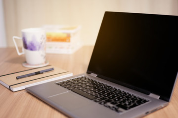 Fototapeta premium computer on a wooden table with a cup and some books