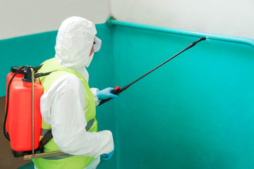 specialist in a protective suit disinfects the entrance