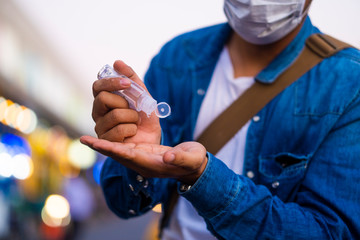 Asian man using wash hand sanitizer gel dispenser, against Novel coronavirus (2019-nCoV) or Wuhan coronavirus at public train station. Antiseptic, Hygiene and Healthcare concept