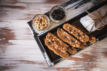Italian biscotti cookies with walnuts and raisins, shot on a dark wooden background. Background for cooking and home baking.