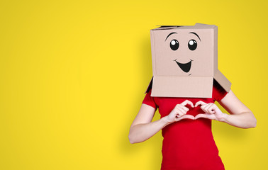 Person with cardboard box on its head and a happy face expression forming a heart with his fingers...