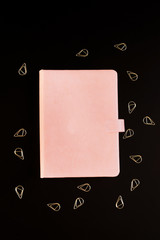 Delicate pink notebook on black background. Spring concept. Place for text.