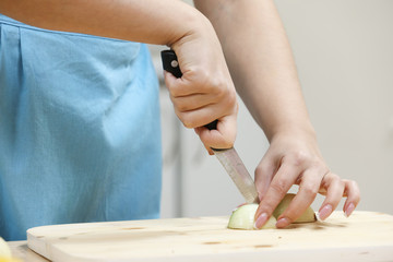 Obraz premium Young woman cooking in kitchen. Housewife preparing vegetables for cooking. Peel onion. Cooking soup