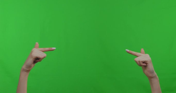 Female hands pointing at empty space over green chromakey background