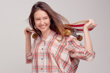 Cool girl student in casual clothes learns to ride a skateboard after classes at the University.