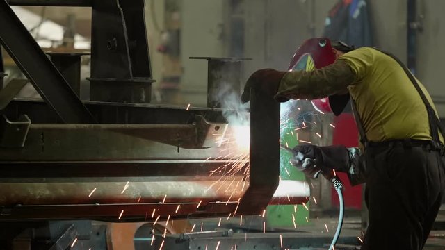 A welder works at a factory and cooks a car body