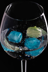 Wine glass with ice different colors on a black background.