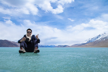 Man standing over landscape of Himalayas mountains and Frozen lake Pangong Tso high grassland lake while winter season for indian and tibetan and foreigner travelers travel visit at Leh Ladakh, India.