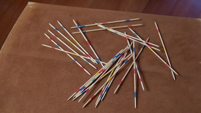 Close up of a hands, a boy is playing a mikado stick, sitting on the floor. Activity ideas for children, home games for kids and family during quarantine of coronavirus