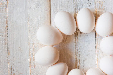 White chicken eggs lying on a white painted wooden surface. Background for livestock products.