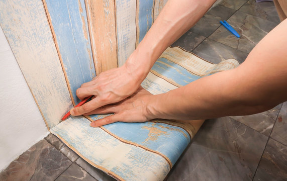 Close up of man hand  cutting of  wallpaper in the room which renovation his home