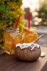 Two summer sour-sweet cups of lemonade with citrus lobules of lemons, oranges, grapefruits on the table under sunshine