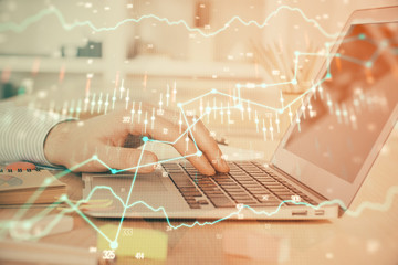 Double exposure of stock market graph with man working on laptop on background. Concept of financial analysis.