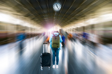 Young solo woman backpacker tourist wait depart time clock to summer adventure voyage journey at train subway platform station with blurred motion speed movement abstract city busy crowded background