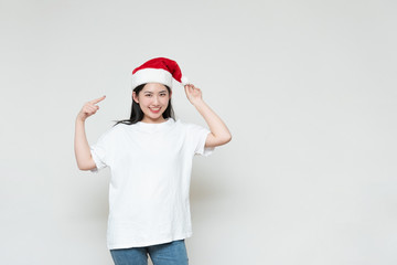 A young asian woman in a Christmas hat stands in front of the white wall