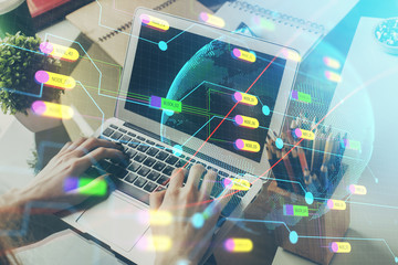 Double exposure of world map hologram with man working on computer on background. Concept of worldwideweb.