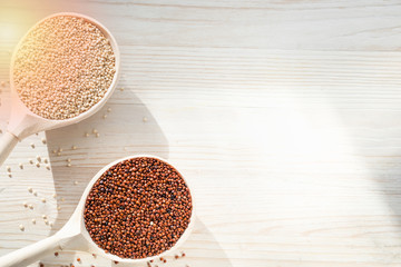 white and red quinoa in wooden spoons on a wooden background