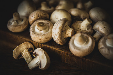 Several champignons lying on a wooden kitchen surface. Background for vegetables.