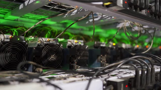 Cryptocurrency mining equipment on large farm. ASIC miners on stand racks mine bitcoin in server room. Blockchain techology application specific integrated circuit. Slider camera.