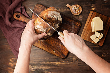 Woman hands cut fresh organic artisan bread. Healthy eating, buy local, homemade bread recipes concept. Top view, flat lay