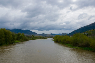 
shore of a mountain river and thunderclouds