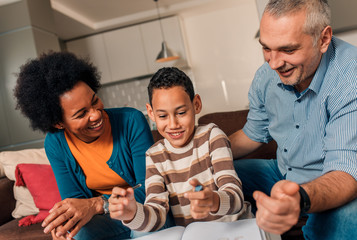 Parents helping their son with his homework at home in living room.