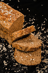 Close-up shot of a whole grain bread and slices on dark background