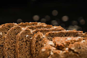 Close-up shot of a whole grain bread and slices on dark background