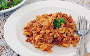 fried macaroni with egg, pork and vegetable in tomato sauce in plate
