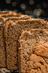 Close-up shot of a whole grain bread and slices on dark background