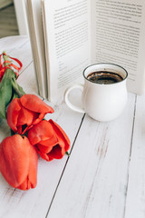 beautiful mug with hot coffee, reading a book in the morning, spring red tulip