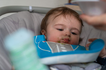 mother feeding her baby boy with a spoon