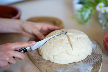 Hands of a girl holding knife and making cross on easy to prepare and healthy, home made irish soda...
