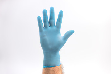 Hand with medical blue latex protective gloves on white background held up as a stop disease sign