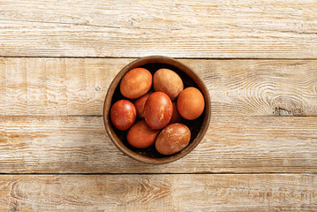 on a wooden light background brown eggs in a cup as a symbol of Easter