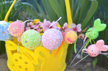 Easter decorative eggs in the grass with flowers and a basket. Easter decoration.