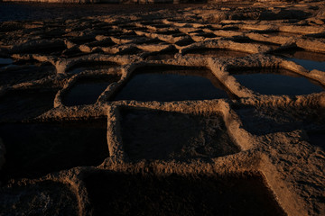 Xlendi's Saltpans at sunset next to Xlendi's tower. 