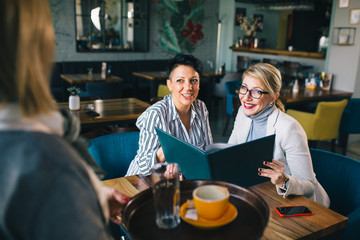 woman looking at the menu and ordering food in restaurant