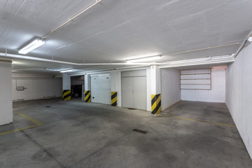 Common garage for parking cars in a multi-storey building with sewer pipes.