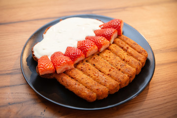 Delicious carrot cake in sour cream sauce with fresh strawberries served on the black serving plate