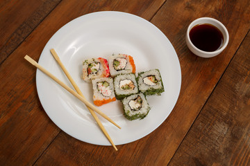 Assorted rolls with salmon and masago caviar on a white plate soy sauce.