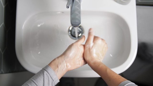 hygiene, health care and safety concept - close up of woman washing hands with soap foam and water