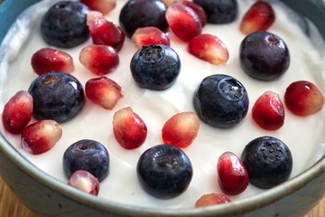 Bowl of yogurt, fresh blueberries, and seeds of pomegranate . Healthy breakfast, close up