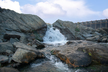a small waterfall with beautiful clouds in the background