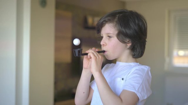 Young boy exercises with deep breathing lung exerciser.
Home exercise for better lung capacity and coughing.