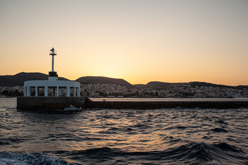 Fototapeta na wymiar Harbor entrance in Greece with lighthouse at sunset