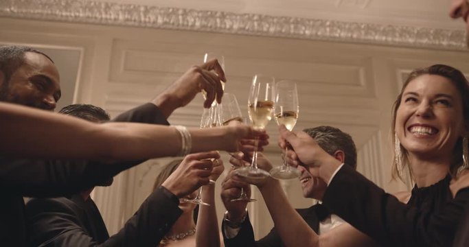 Multi-ethnic friends toasting and drinking wine at a party. Group of men and women celebrating new years eve with drinks.
