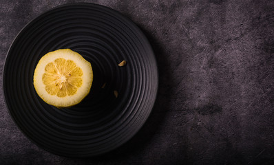 
Half a yellow lemon on a black plat. Aerial view. Horizontal format.
