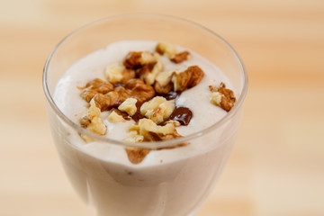 Top view of ice cream smoothie with banana and nuts sprinkled with chocolate.