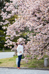 Young woman enjoying cherry blossom in Japanese garden in spring day